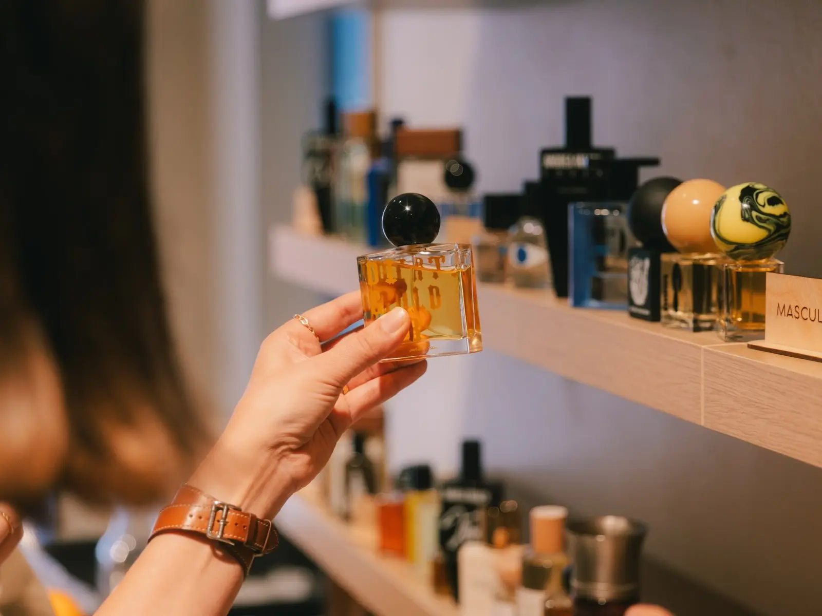 A guest considering a fragrance at the shelves inside The Drydown boutique